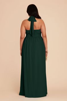 a woman in a dark green dress is looking back at the camera and she has her hands on her hips