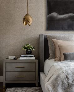 a bedroom with a bed, nightstand and painting on the wall above it in gold