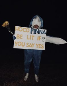 a man dressed as a shark holding a sign that says hoco finna be lit if you say yes