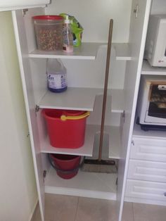 a white shelf with some buckets and a mop in it's corner