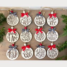 twelve christmas ornament ornaments hanging on a wooden board with pine branches and red ribbon