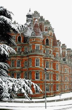 a large red brick building with snow on the ground and trees in front of it