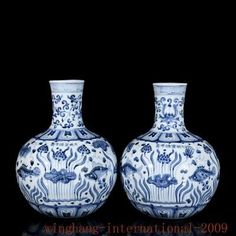 two blue and white vases sitting next to each other on a black table top