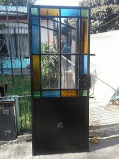 a black cabinet with multicolored glass panels on the front and back doors, sitting next to a fence