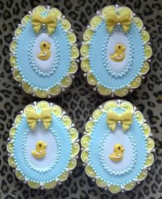 four cupcakes decorated with blue and yellow icing on a leopard print surface