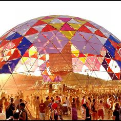 a large group of people standing in front of a big dome structure with many colors on it