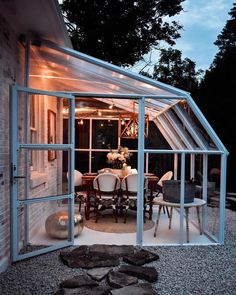 an outdoor dining area is lit up with string lights and glass doors that lead into the backyard