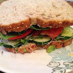 a sandwich with lettuce, tomato and cucumber on it sitting on a plate