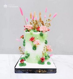 a white and green cake with pink flowers on top