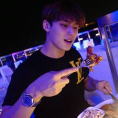 a young man holding a fork and knife in his hand while eating pizza on a plate