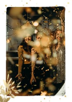 three women standing next to each other with confetti in front of their faces