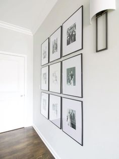 a white wall with black and white pictures hanging on it's side, along with a lamp