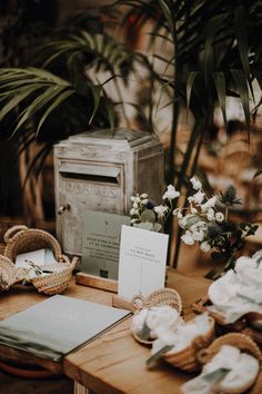 a wooden table topped with lots of plates and napkins next to potted plants