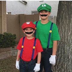 two boys dressed up as mario and luigi in front of a tree with fake moustaches on their faces