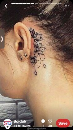 a woman's ear with a flower tattoo on her left side behind the ear