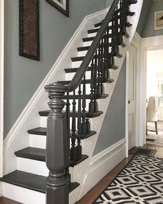 a black and white staircase in a house with gray walls, carpeted flooring and framed pictures on the wall