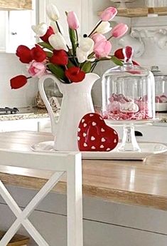 a vase filled with pink and white tulips on top of a wooden table