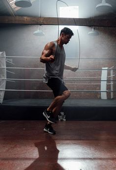 a man standing on top of a hard wood floor in front of a boxing ring