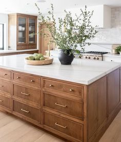 a large kitchen with an island in the middle and wooden cabinets on both sides, surrounded by white countertops