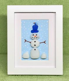 a white frame with a blue snowman in the center on a green surface,