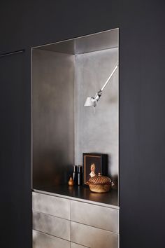 a mirror is on the wall above a dresser in a room with black walls and furniture