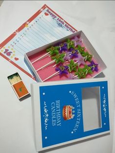 there is a birthday card in the box with flowers on it and matchessticks