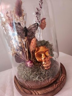 a glass cloche with flowers and a skull in it