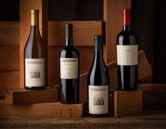 three bottles of wine sitting on top of a wooden shelf