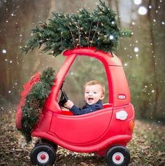 a little boy driving a red car with a christmas tree on the roof and inside