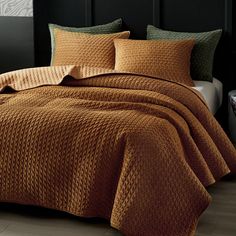 a bed covered in brown bedspread and pillows