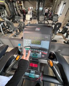 a person on a treadmill in a gym with other machines and people walking around