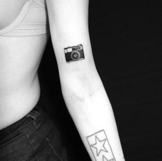 a woman's arm with a camera tattoo on the left side of her right arm