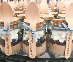 mason jars filled with marshmallows and chocolate chip cookies are displayed on a table