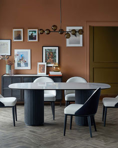 a dining room table with white chairs and pictures on the wall above it, along with other furniture