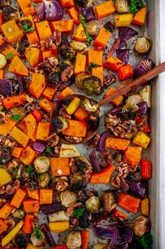 roasted vegetables in a baking dish with wooden spoons and spices on the side, ready to be eaten