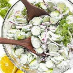 a bowl filled with cucumber salad and a wooden spoon