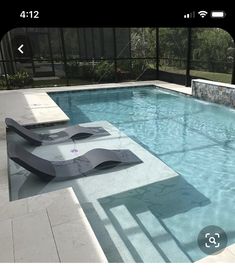 an empty swimming pool surrounded by glass walls and tiled flooring, with lounge chairs on the side