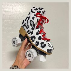 a hand holding up a pair of shoes that are decorated with black and white leopard print