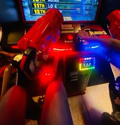 two people playing video games in front of a computer screen with red and blue lights