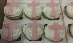 cupcakes with frosting and pink crosses on them are displayed in a box