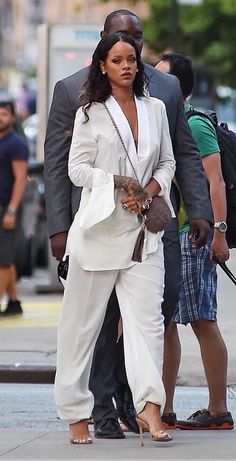 a man and woman are walking down the street with an umbrella in hand, one is wearing a white suit