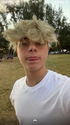 a woman with blonde hair is taking a selfie in front of a park area