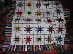 a quilt is laying on top of a chair and it has many different colored stars