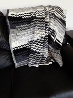 a black and white blanket sitting on top of a couch next to a leather chair