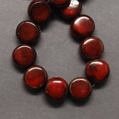 a red beaded bracelet with round beads on a gray surface, in the shape of a circle