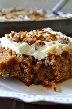 a piece of carrot cake on a plate with cream cheese frosting and pecans