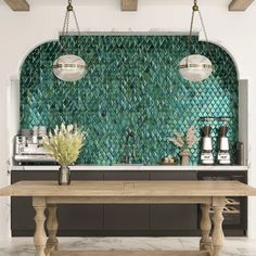 a kitchen with green tiles on the wall and wooden table in front of it, along with two pendant lights