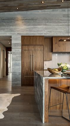 a modern kitchen with wooden cabinets and marble counter tops, along with an island in the middle