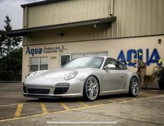 a silver sports car parked in front of a building with the word acura written on it