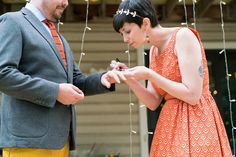 a man and woman standing next to each other in front of a string of lights